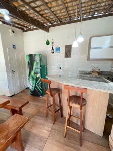 a kitchen with a large counter with stools and a table at Casa de praia na caueira com piscina in Itaporanga dʼAjuda