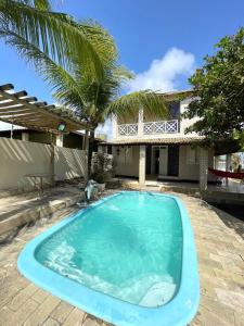 a swimming pool in front of a house with a palm tree at Casa de praia na caueira com piscina in Itaporanga dʼAjuda