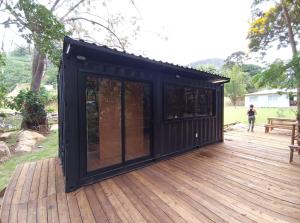 a black shipping container on a wooden deck at Vibe Container CAPARAÓ AMARELO in Pedra Menina