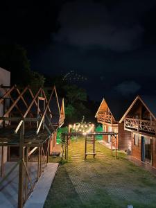 a group of houses at night with lights at Pousada Chalé Flor de Hibisco 1 in Penha