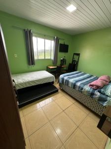 a bedroom with two beds and a table and a window at Apto Natureza Verde Manauara II in Manaus