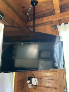 a large screen tv in a room with wooden walls at Pousada Chalé Flor de Hibisco 1 in Penha