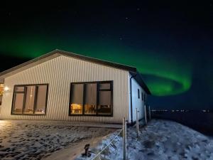a building with the aurora in the sky at Skidbakki Guesthouse in Kross