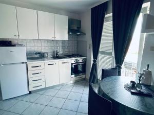 a kitchen with white cabinets and a table in it at Cosy apartment in Pag / 26 m² / Sea view in Pag