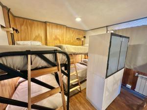a room with three bunk beds and a refrigerator at Hostel TRUFA in San Carlos de Bariloche