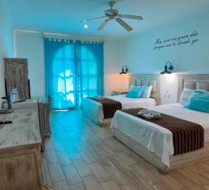 a bedroom with two beds and a ceiling fan at Coco Rio Hotel - Mamitas Beach Area in Playa del Carmen