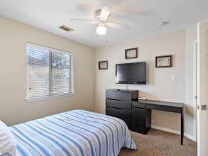ein Schlafzimmer mit einem Bett und einem Schreibtisch mit einem Fernseher in der Unterkunft Cozy Sunterro Serenity in North Austin Pet Friendly in Austin