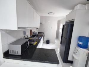 La cuisine est équipée d'un réfrigérateur noir et d'un four micro-ondes. dans l'établissement excelente Cobertura no centro de Bertioga, à Bertioga