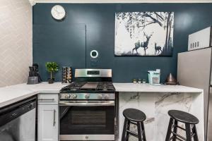 Una cocina con estufa y dos taburetes de bar. en Comfy Studio with King Bed & Full Kitchen - Near Attractions, en Houston