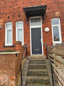 a brick building with a black door and stairs at The Old Band Accommodation 1 kingsize bed and 1 Sofa Bed available in Higham Ferrers