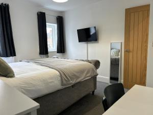 a bedroom with a bed and a flat screen tv at The Old Band Accommodation 1 kingsize bed and 1 Sofa Bed available in Higham Ferrers