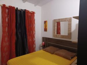 a bedroom with a yellow bed and red curtains at Charmant bungalow à MOULE in Le Moule