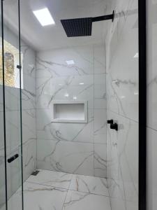 a shower with white marble walls and a glass door at Pousada Praia Grande de Palmas in Praia de Palmas +24 photos