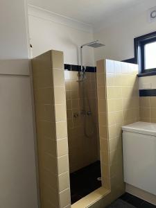 bagno con doccia e piastrelle gialle di Hawkesview a Vincentia
