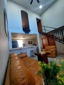 a living room with a brown leather couch and stairs at depa del Oso in Nuevo Casas Grandes