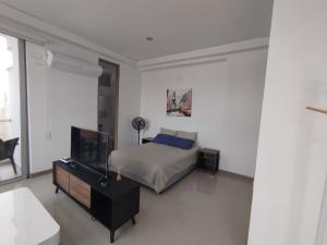 a bedroom with a bed and a flat screen tv at Apartaestudio Jacuzzi Centro Comercial Buena vista Restaurantes Gimnasio ALTOPRADO in Barranquilla