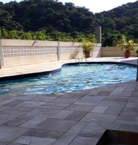 a swimming pool with blue water and a wall at Apartamento enseada in Guarujá