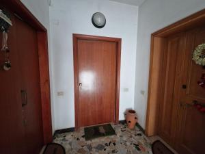 a hallway with a wooden door and a clock on the wall at Bagnuz's Home in Scandicci