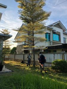 two people walking in front of a house with a tree at D'PrinceDream in Port Dickson
