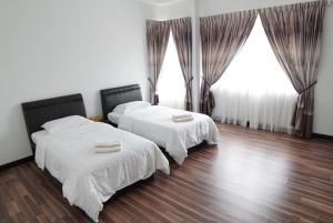 two beds in a room with wooden floors and windows at D'PrinceDream in Port Dickson