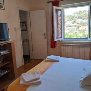 a bedroom with a large bed with a window and towels at Apartments Kat in Splitska +49 photos