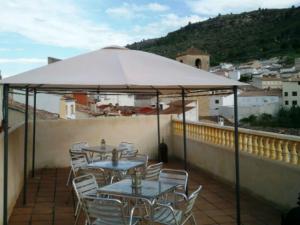 a patio with tables and chairs under an umbrella at Casa Rural Valle del Cabriel in Enguídanos