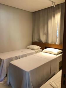 a room with three beds and a window at Apto Salinas Premium - 2 quartos - 1 suíte in Salinópolis +19 photos