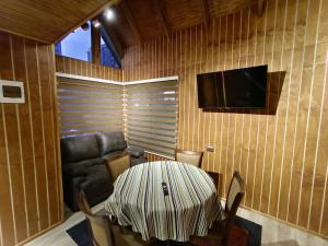 a room with a table and a couch and a television at Cabaña Drak Bosque y Mar 2 in Tomé