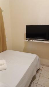 a bedroom with a bed and a flat screen tv at Hostel X DE CARAIVA in Caraíva