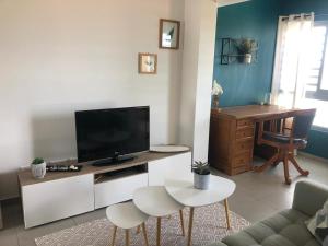 a living room with a tv and two white chairs at Appartement TERUPE in Papeete