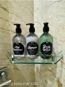 trois bouteilles de savon sur une étagère en verre dans une salle de bain dans l'établissement Cozzi Homestay Sibu, à Sibu 1 autre photo