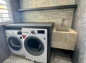 a washer and dryer in a kitchen with a sink at Cozzi Homestay Sibu in Sibu