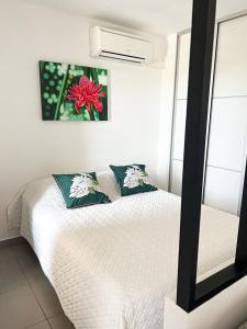 a bedroom with a white bed and a mirror at Appartement TERUPE in Papeete