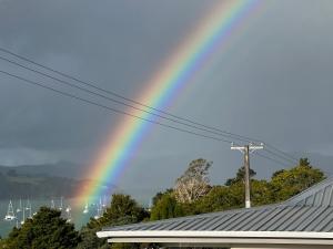 a rainbow in the sky over a house at Fantail Cottage in Opua