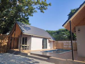 a house with a swimming pool and a wooden fence at Baansuan Tham Ma Chad Homestay in Suphan Buri