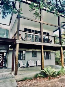 un edificio con una terraza y dos sillas. en Sandy Escape Holiday House Kingfisher Bay Resort, en Kingfisher Bay