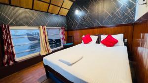 a bedroom with a bed with red pillows and a window at Alleppey Houseboat Viswas Cruise in Alleppey +8 photos