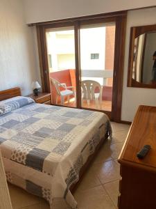 Un dormitorio con una cama y vista a un balcón. en Romeo 4, en Villa Gesell