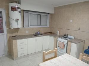 Una cocina con gabinetes blancos y un horno de estufa. en Residencia Los Miottis, en Necochea 3 fotos más