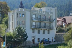 a white building with a car parked in front of it at Hotel Three Korony in Skhidnitsa