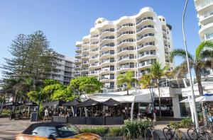 a large building with tables and umbrellas in front of it at ZANZ205- Exclusive Outdoor Spa with Ocean Glimpses in Mooloolaba