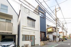 東京にあるAkisapo Stay Itabashi - アキサポステイ本蓮沼の白い建物の前に停車する車