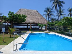 a swimming pool at a resort with a thatch roof at Rancho Joya Del Mar in Sonsonate