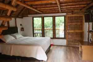 ein Schlafzimmer mit einem Bett und einem großen Fenster in der Unterkunft Alojamiento rural Ecoparque La Motilona Paicol, Huila - Cabaña la Motilona in Paicol