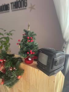 a television sitting on a table with a christmas tree at Thương Thương Homestay in Xuan An