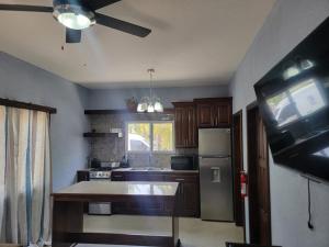 a kitchen with wooden cabinets and a ceiling fan at Tuquil-HA in Ladyville