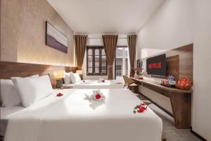 ein Hotelzimmer mit zwei Betten und einem Schreibtisch in der Unterkunft Kly Luxury Hotel in Hue