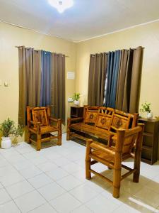 a living room with two wooden chairs and curtains at GoodStay Angeles in Angeles