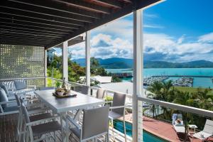 Un balcón con mesa y sillas y vista al agua. en Kims On Kara, en Airlie Beach