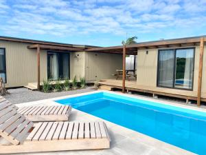 a house with a swimming pool and two chairs at Mañanita del Este reserva con seña in Barra del Chuy